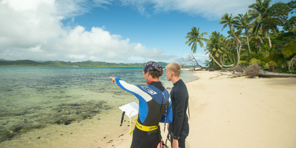 Two volunteers in the marine conservation program surveying the ocean Off of the coast of Caqalai Island, Fiji.