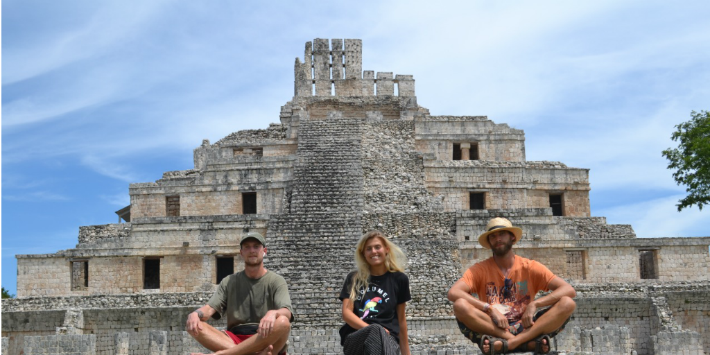 three people sitting in front of ruins