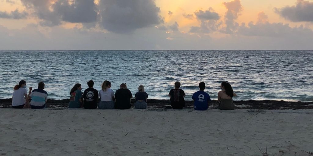 Volunteers sitting on the beach watching the sunset together